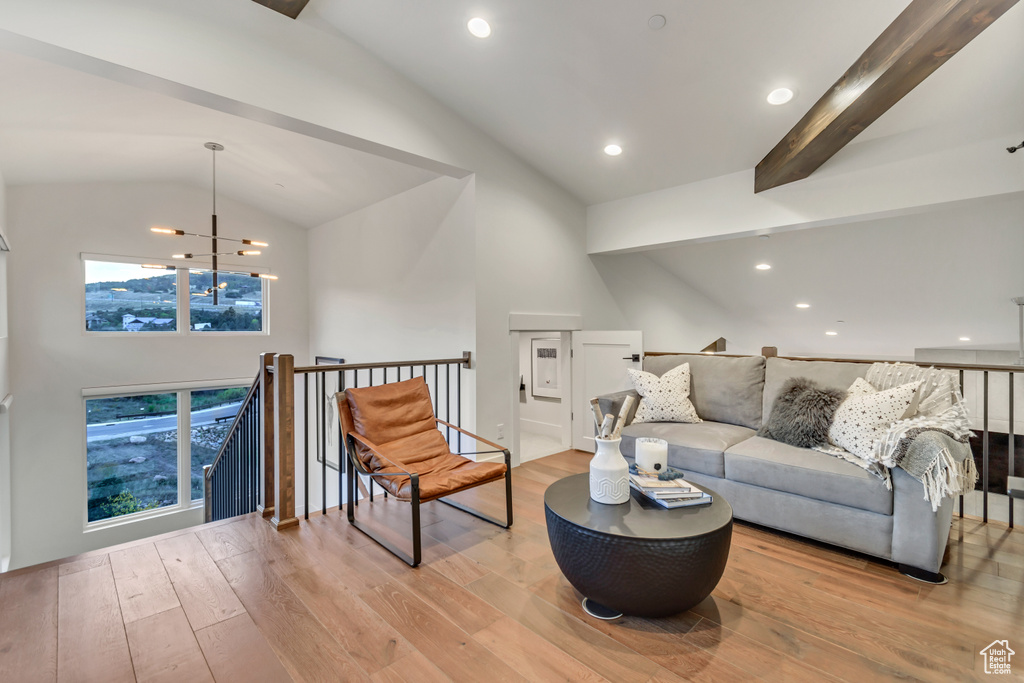 Living room featuring a notable chandelier, light hardwood / wood-style floors, beamed ceiling, and plenty of natural light