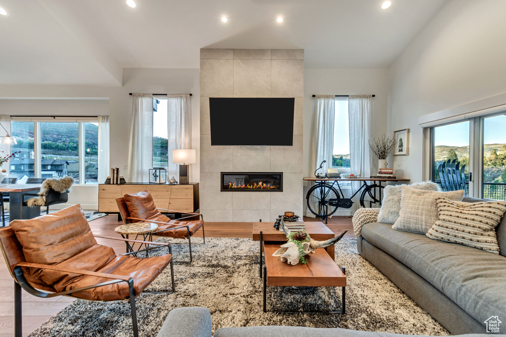 Living room with hardwood / wood-style floors, a tiled fireplace, and tile walls