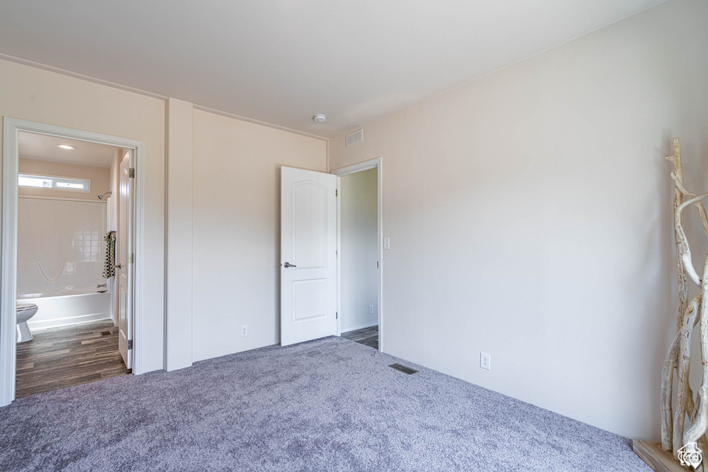 Unfurnished bedroom featuring hardwood / wood-style floors and ensuite bathroom