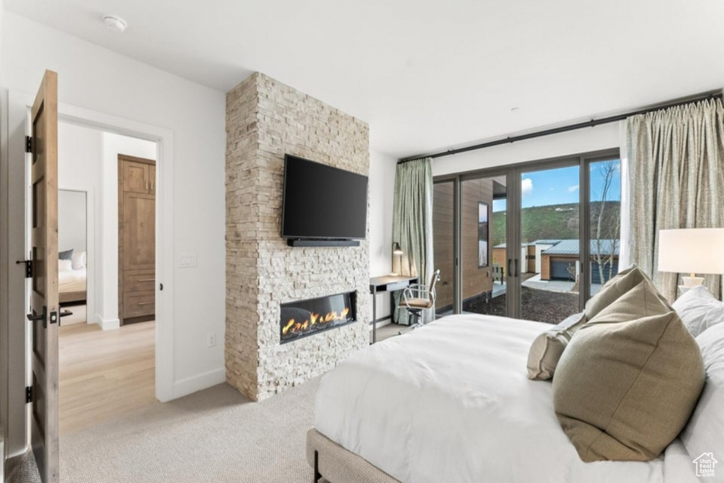 Bedroom with access to exterior, light hardwood / wood-style floors, and a fireplace