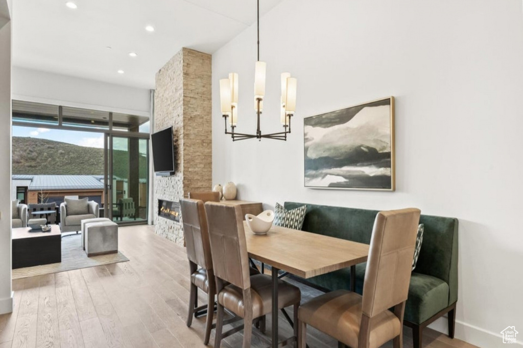 Dining area with a fireplace, a chandelier, and light wood-type flooring