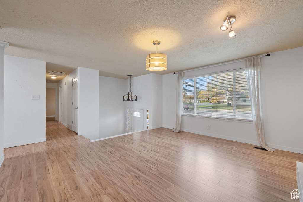 Empty room with light wood-type flooring and a textured ceiling