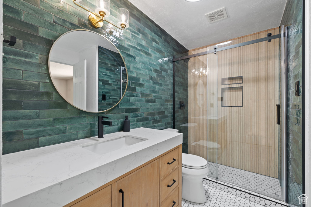 Bathroom with walk in shower, vanity, toilet, and tile walls