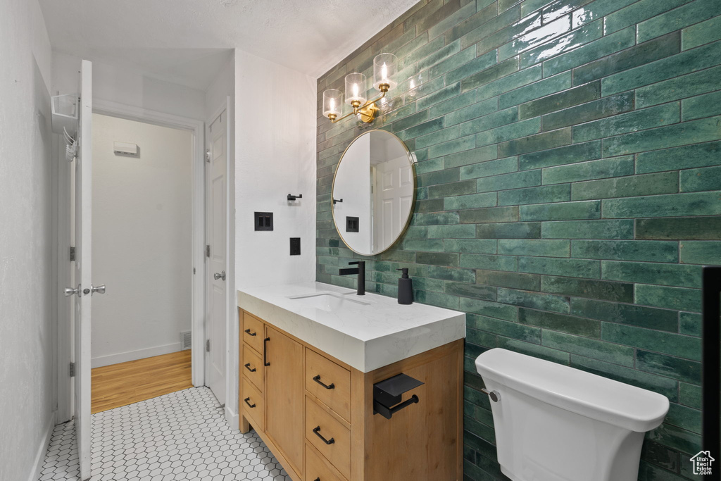 Bathroom featuring tile walls, vanity, tile patterned floors, and toilet