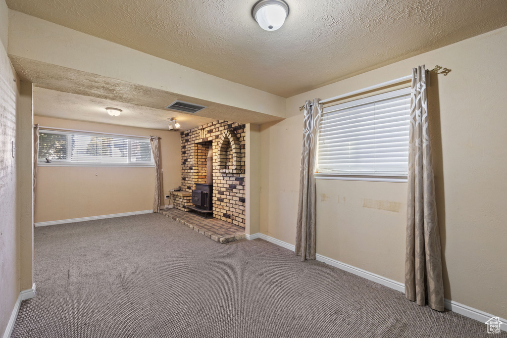 Interior space with a wood stove, carpet, and a textured ceiling