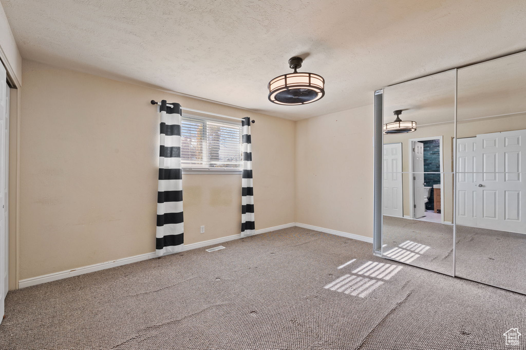 Unfurnished bedroom with a closet, a textured ceiling, and carpet flooring