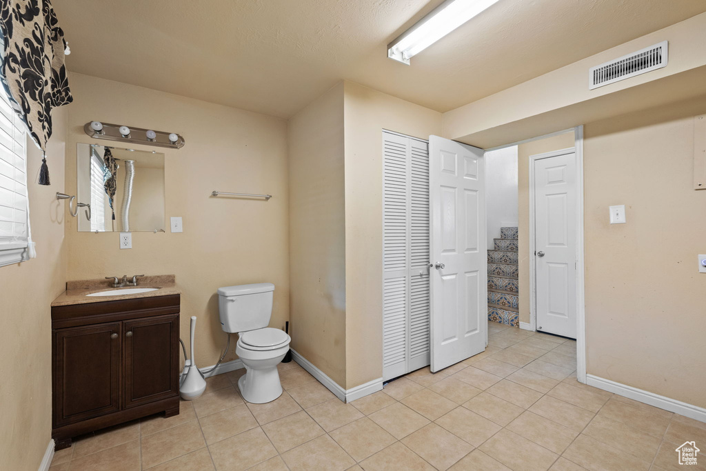 Bathroom featuring vanity, tile patterned floors, and toilet