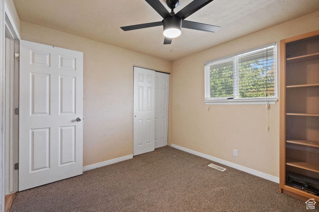 Unfurnished bedroom featuring ceiling fan and carpet