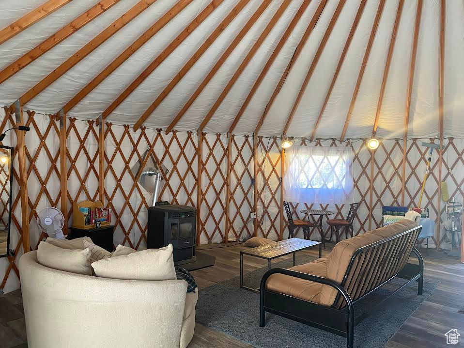 Living room with vaulted ceiling, hardwood / wood-style floors, and a wood stove