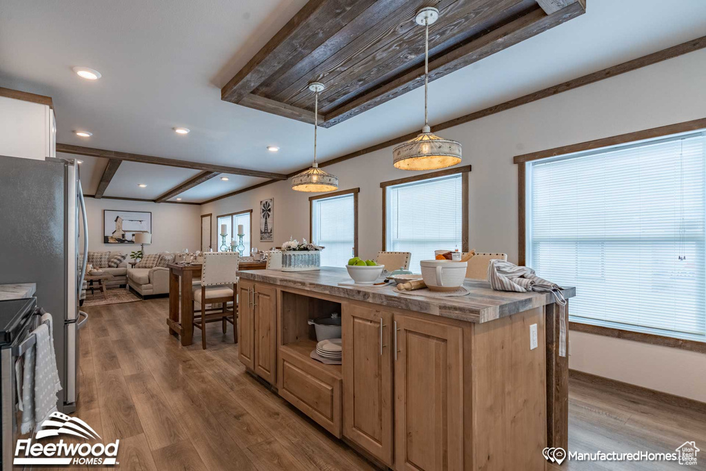 Kitchen with a center island, light hardwood / wood-style floors, pendant lighting, and stainless steel refrigerator