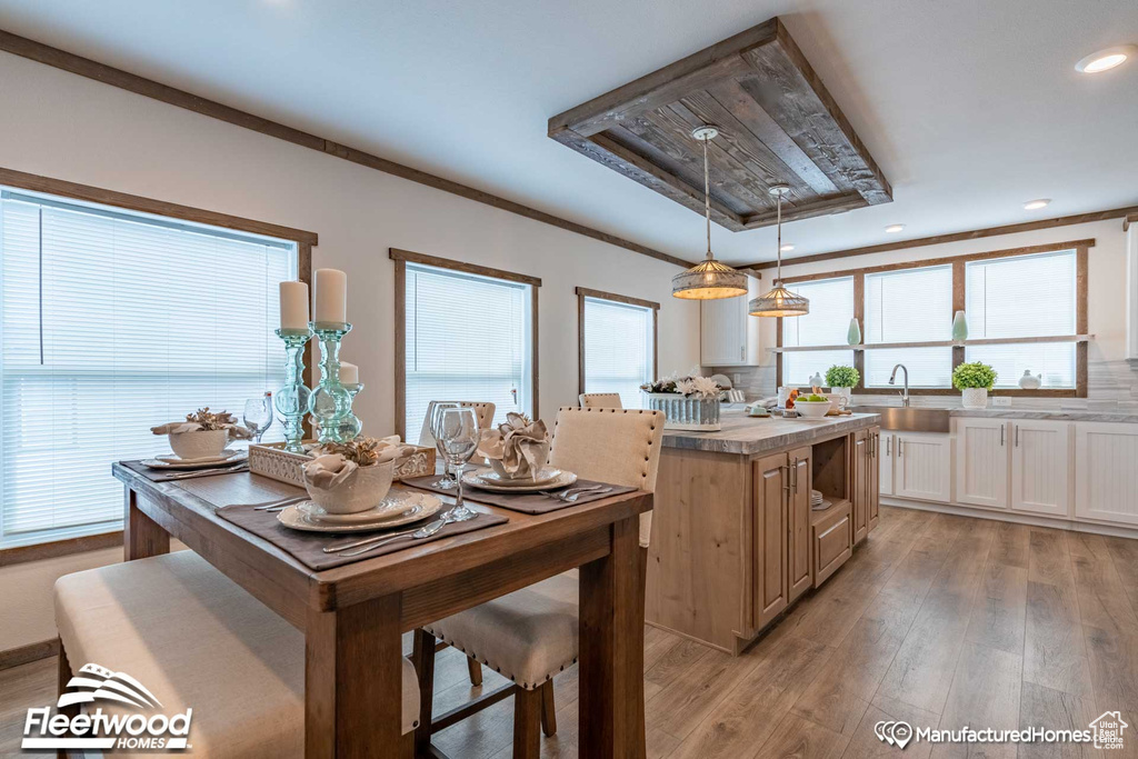 Kitchen with light hardwood / wood-style floors, tasteful backsplash, ornamental molding, and pendant lighting