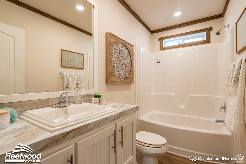 Full bathroom with tub / shower combination, ornamental molding, wood-type flooring, vanity, and toilet