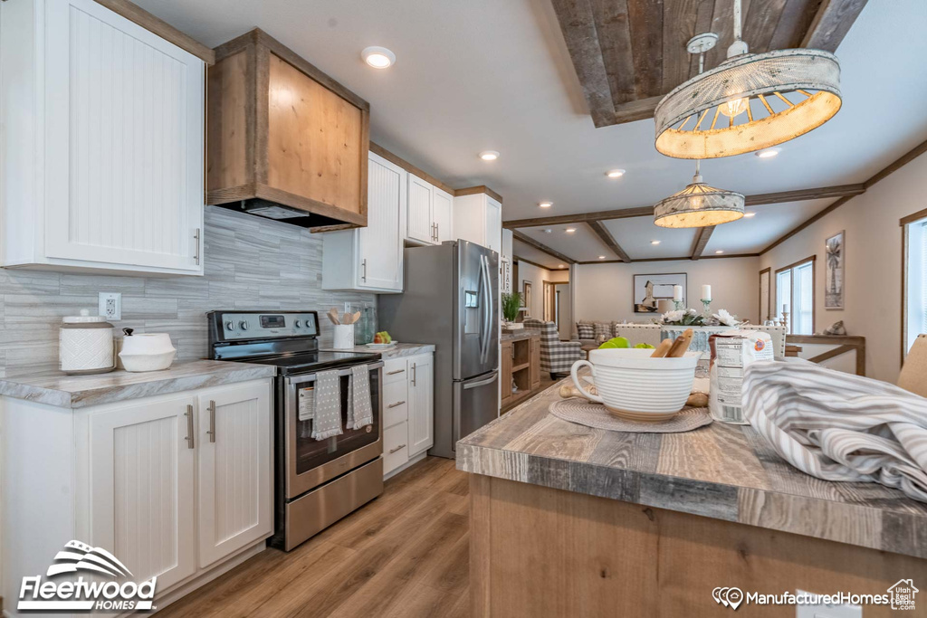 Kitchen with decorative light fixtures, light wood-type flooring, appliances with stainless steel finishes, tasteful backsplash, and white cabinetry