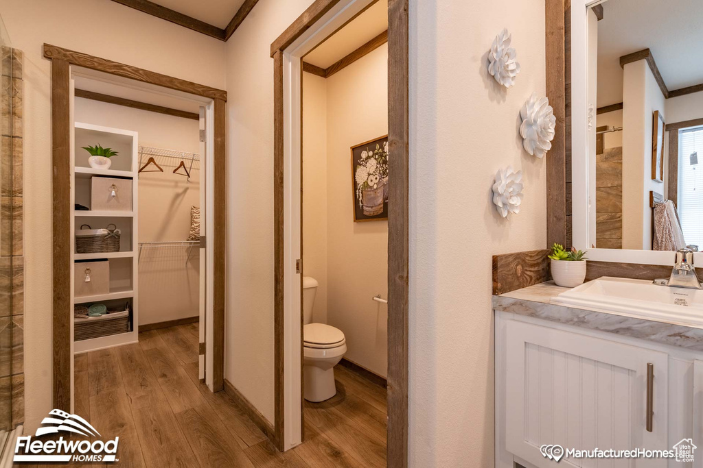 Bathroom with wood-type flooring, vanity, crown molding, and toilet