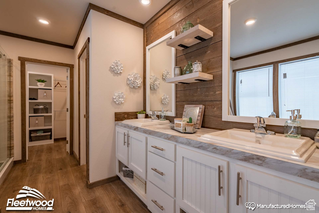 Bathroom featuring wood walls, crown molding, hardwood / wood-style floors, and dual bowl vanity