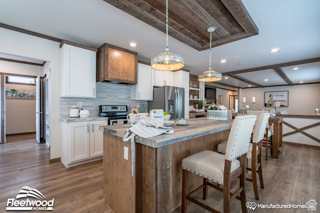 Kitchen with decorative backsplash, a kitchen island, wood-type flooring, white cabinetry, and stainless steel appliances