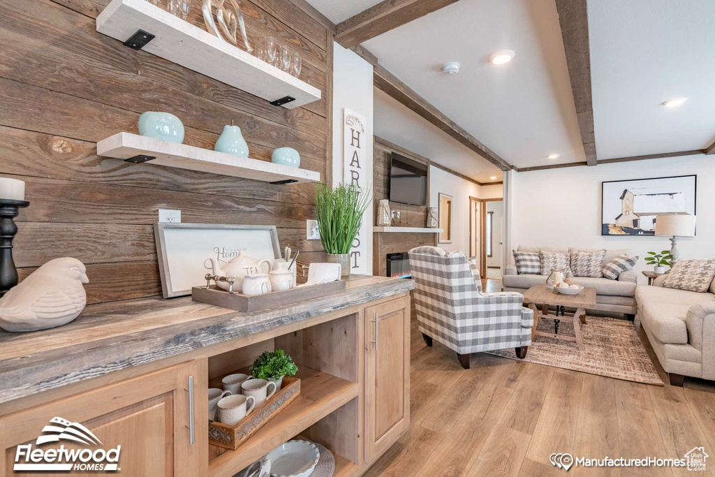 Living room with light wood-type flooring, beamed ceiling, and wooden walls