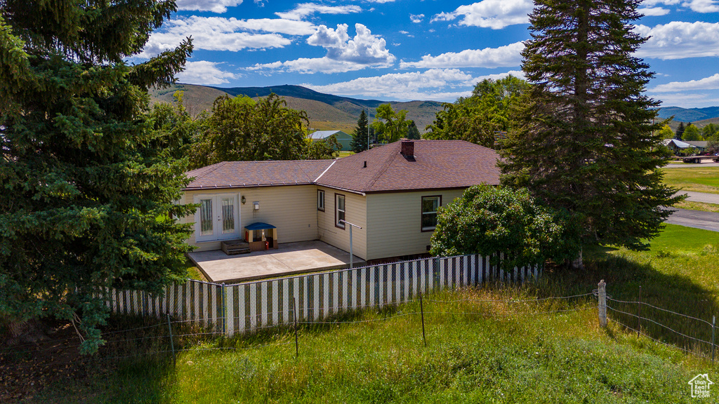 Back of property featuring a mountain view, a patio area, and french doors