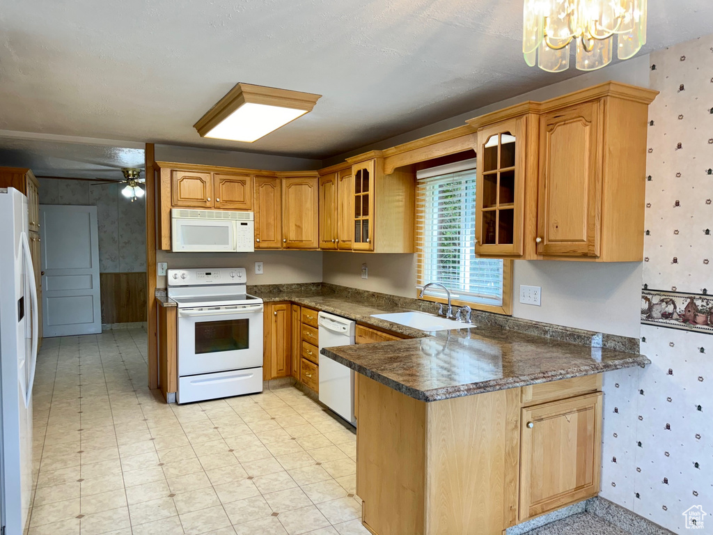 Kitchen featuring ceiling fan with notable chandelier, light tile patterned floors, sink, kitchen peninsula, and white appliances