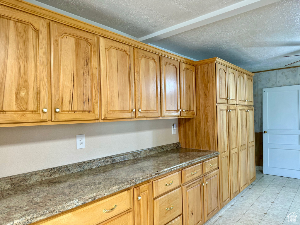 Kitchen featuring dark stone countertops, a textured ceiling, and light tile patterned floors