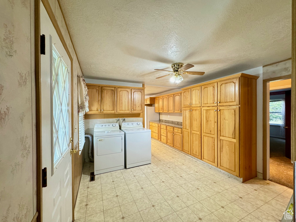 Washroom featuring cabinets, washer and dryer, a textured ceiling, light colored carpet, and ceiling fan