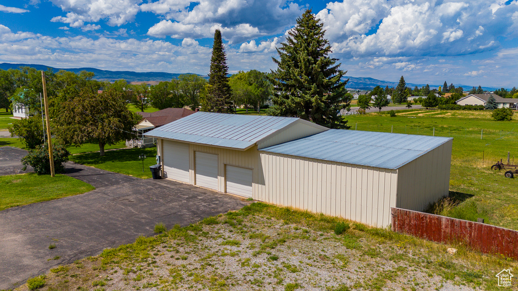 Exterior space featuring a lawn, a mountain view, an outdoor structure, and a garage