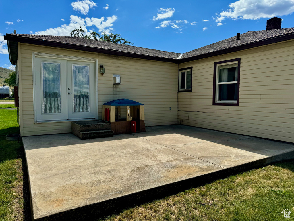 Rear view of house featuring a patio, a yard, and french doors