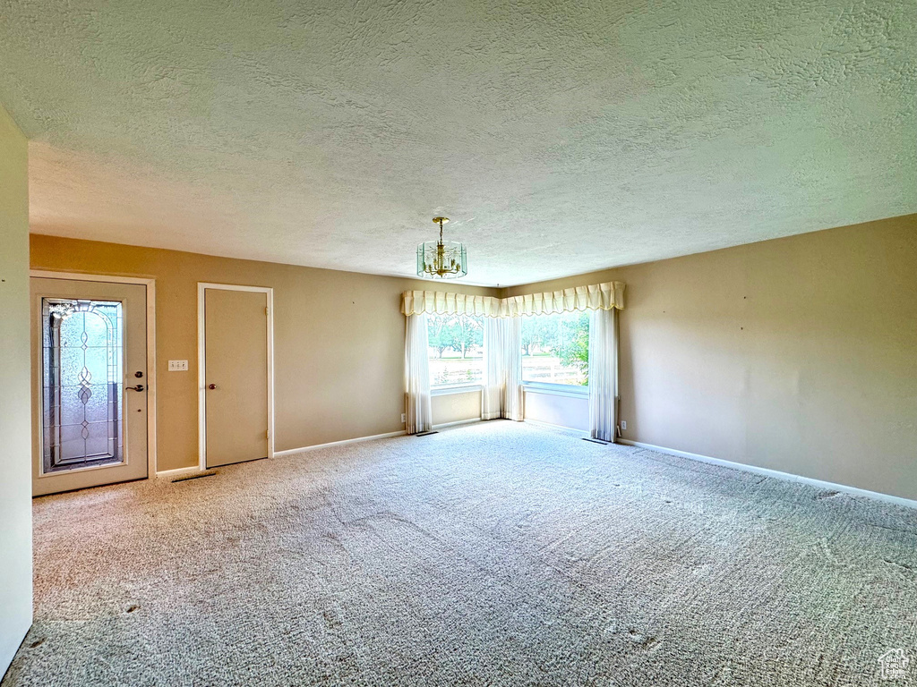 Empty room featuring a textured ceiling and carpet flooring