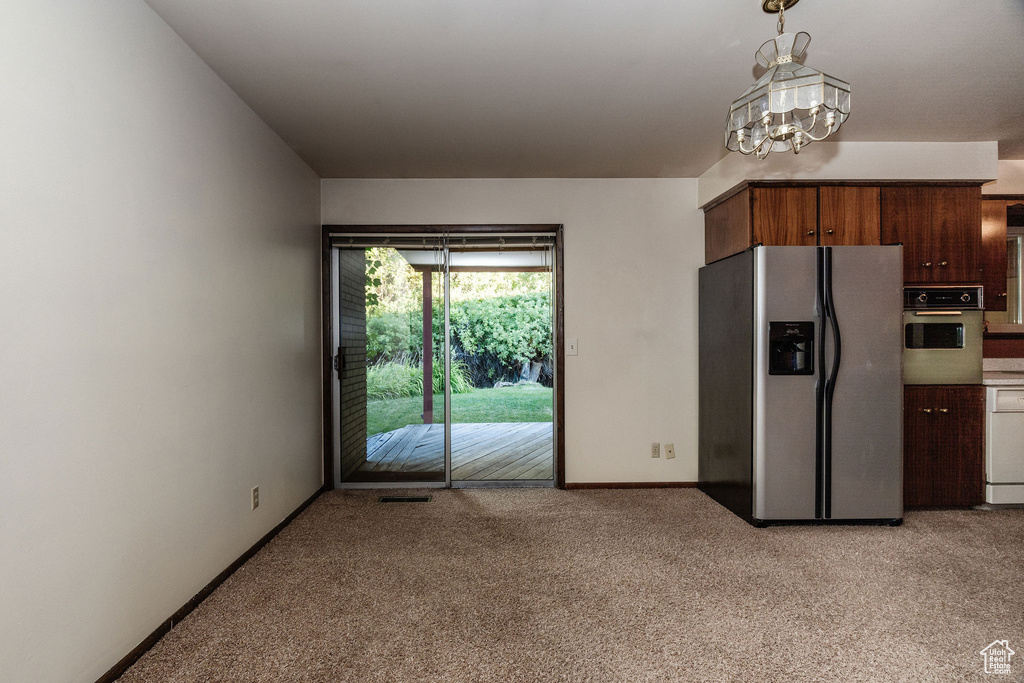 Kitchen featuring stainless steel appliances, light colored carpet, an inviting chandelier, and hanging light fixtures