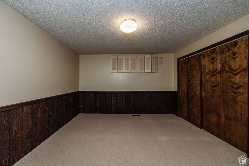 Empty room featuring a textured ceiling and carpet flooring