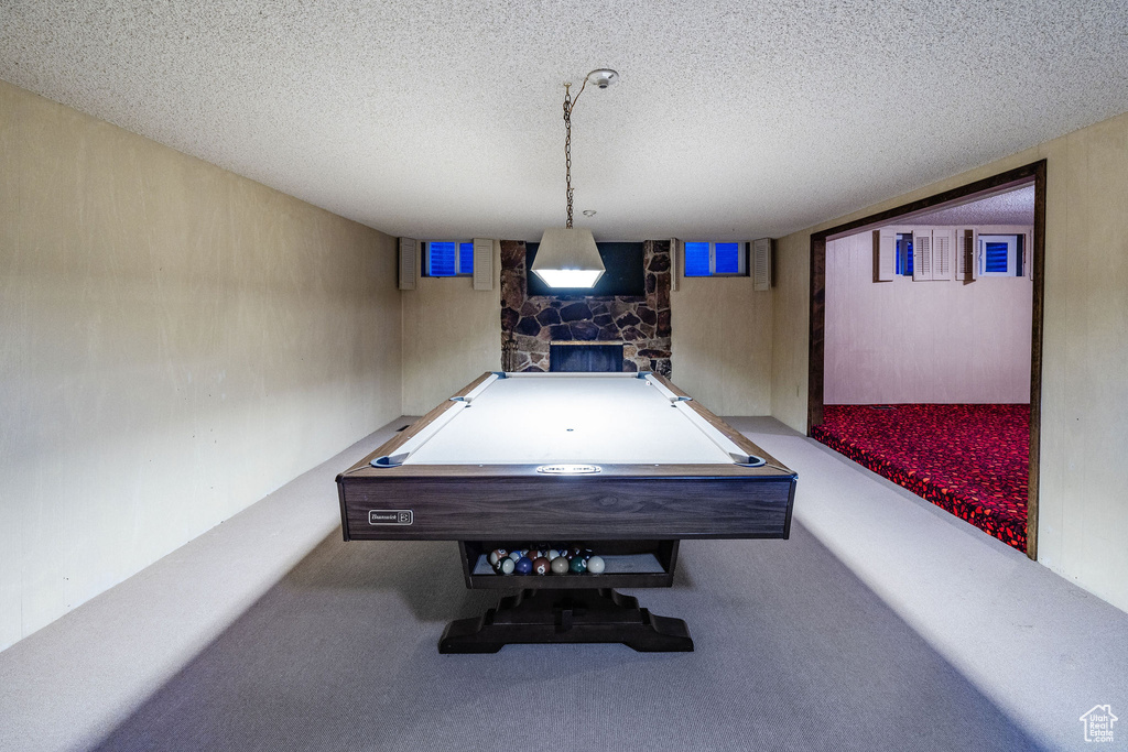 Playroom with pool table, a fireplace, and a textured ceiling