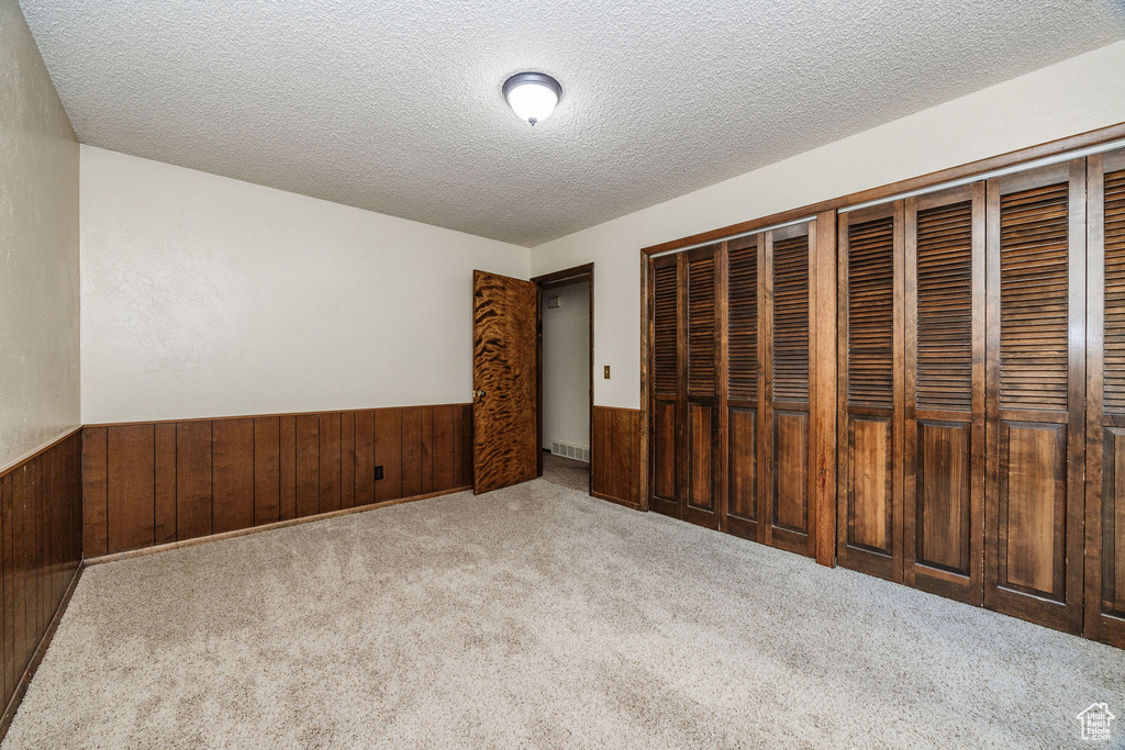 Unfurnished bedroom featuring light carpet, a textured ceiling, and a closet