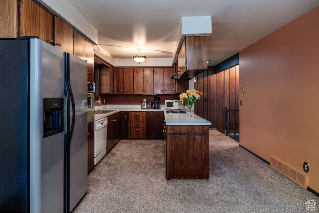 Kitchen with light carpet, white appliances, and sink