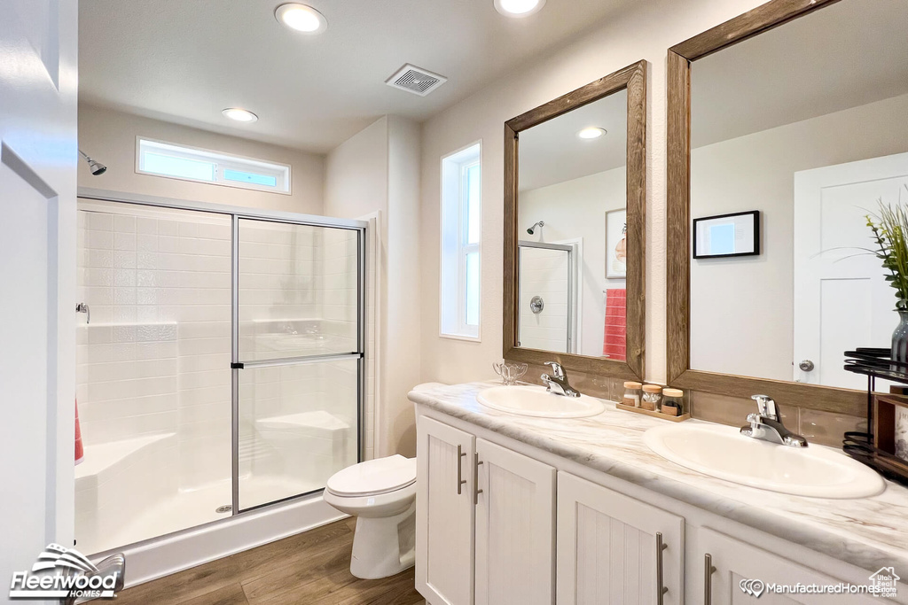 Bathroom with hardwood / wood-style flooring, double vanity, a shower with door, and toilet