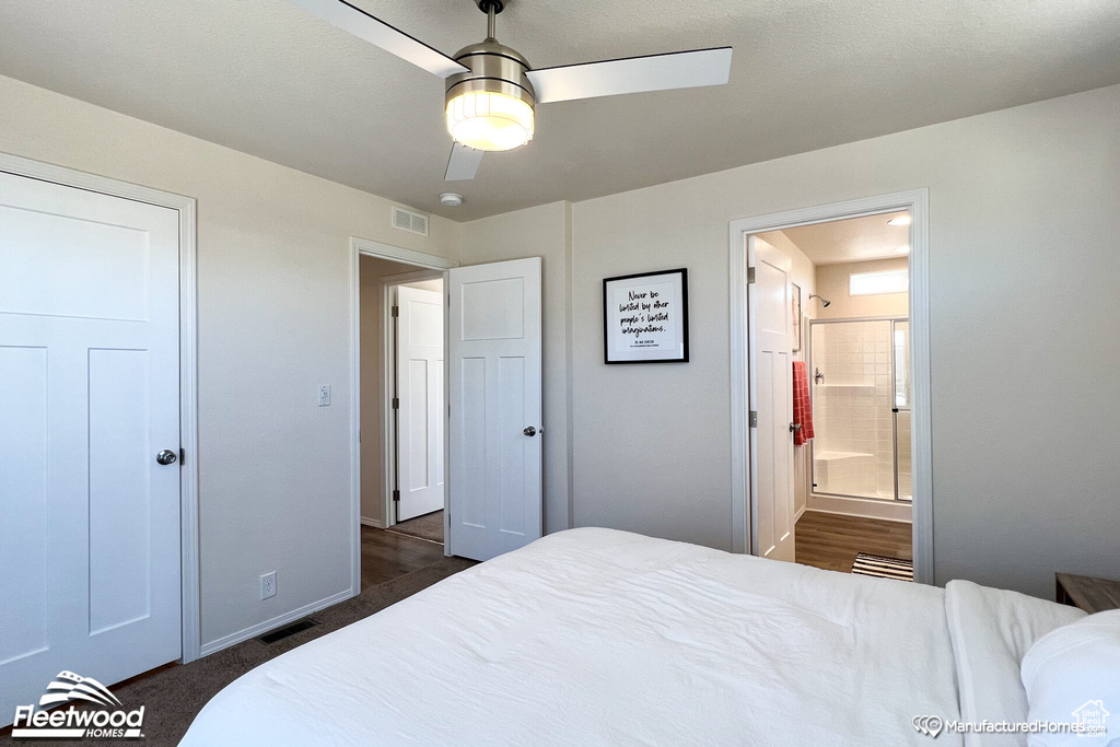 Bedroom with ceiling fan, ensuite bathroom, and dark colored carpet