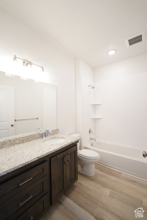 Full bathroom with toilet, vanity, wood-type flooring, and shower / bath combination