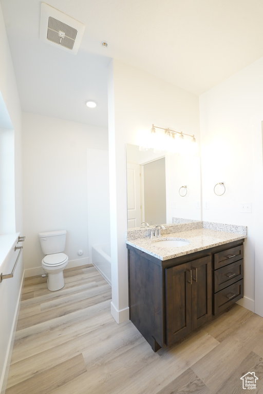 Bathroom with hardwood / wood-style floors, toilet, and vanity