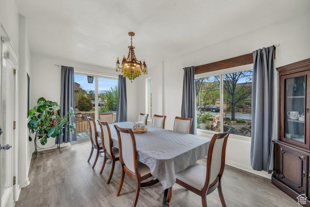 Dining area featuring plenty of natural light, light hardwood / wood-style flooring, and an inviting chandelier