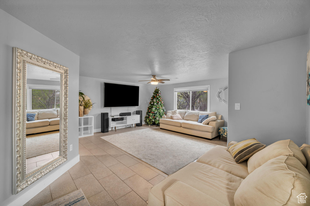 Living room with a textured ceiling, ceiling fan, and light tile patterned flooring