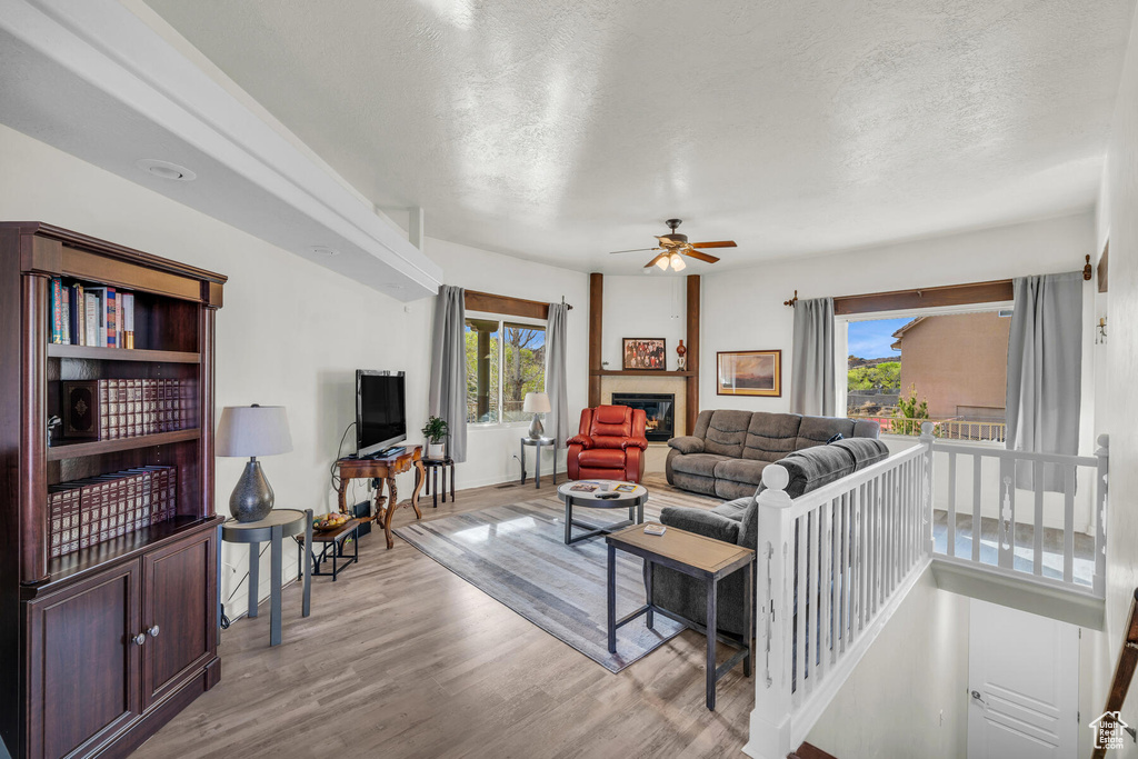 Living room featuring a textured ceiling, ceiling fan, and light wood-type flooring