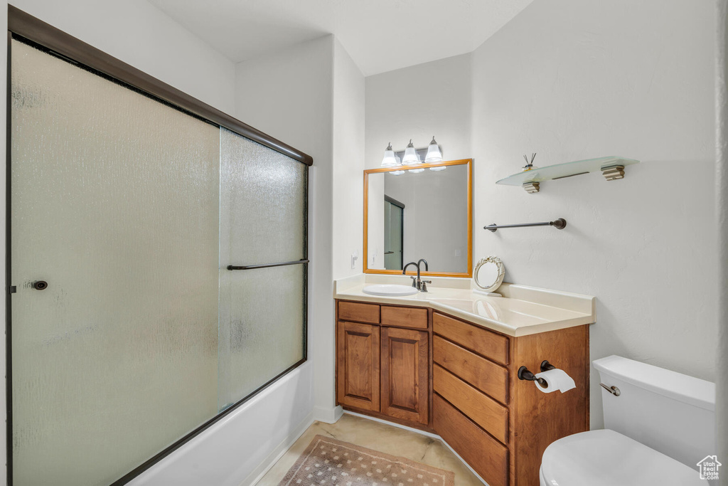 Full bathroom with tile patterned flooring, vanity, shower / bath combination with glass door, and toilet
