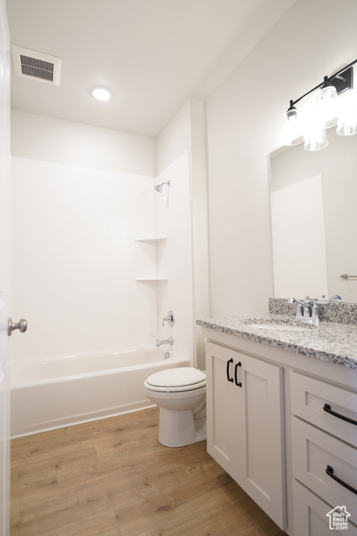 Full bathroom with hardwood / wood-style flooring, vanity, tub / shower combination, and toilet