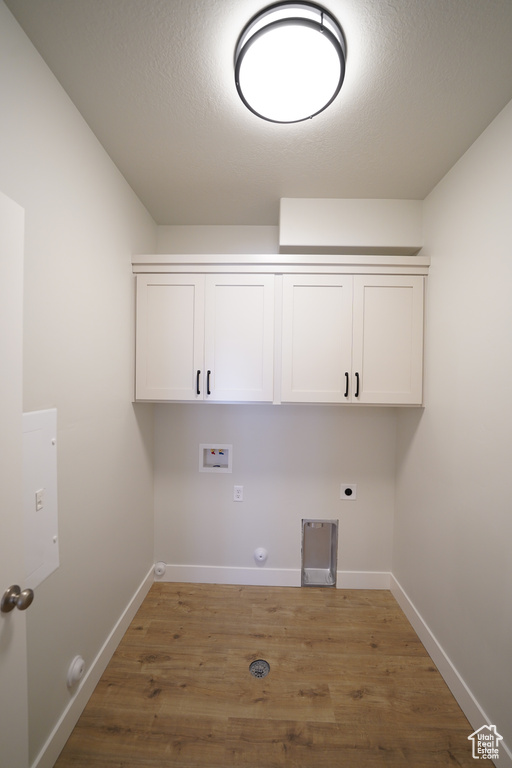 Washroom featuring electric dryer hookup, wood-type flooring, washer hookup, cabinets, and hookup for a gas dryer