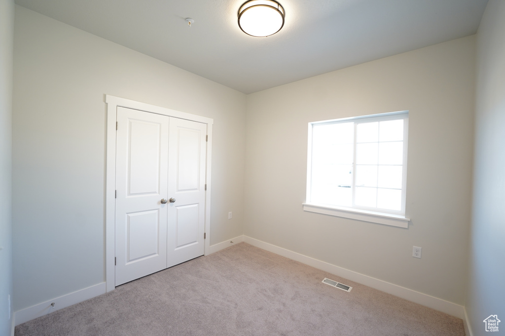 Unfurnished bedroom featuring a closet and light colored carpet