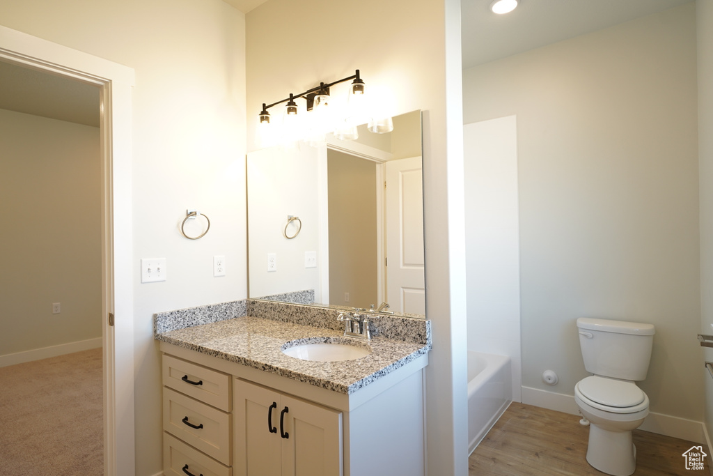 Full bathroom featuring toilet, washtub / shower combination, vanity, and hardwood / wood-style flooring