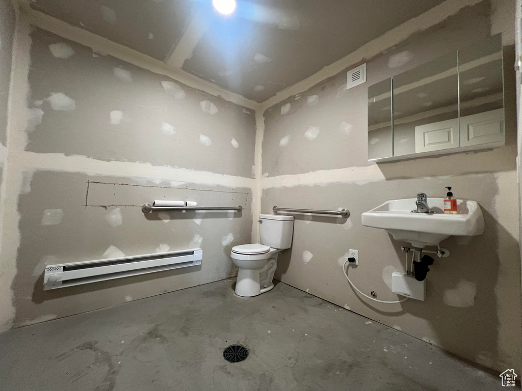 Bathroom featuring toilet, concrete floors, and a baseboard heating unit