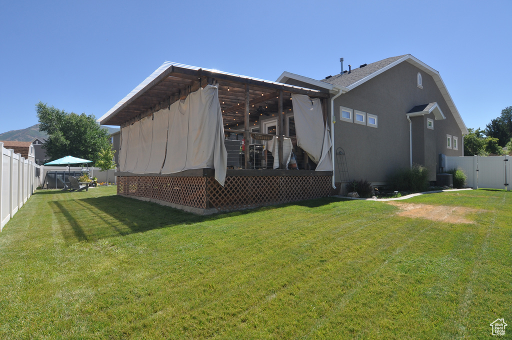 Back of property with a wooden deck and a yard