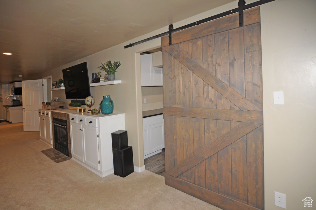 Kitchen with light colored carpet, white cabinetry, a barn door, and wine cooler