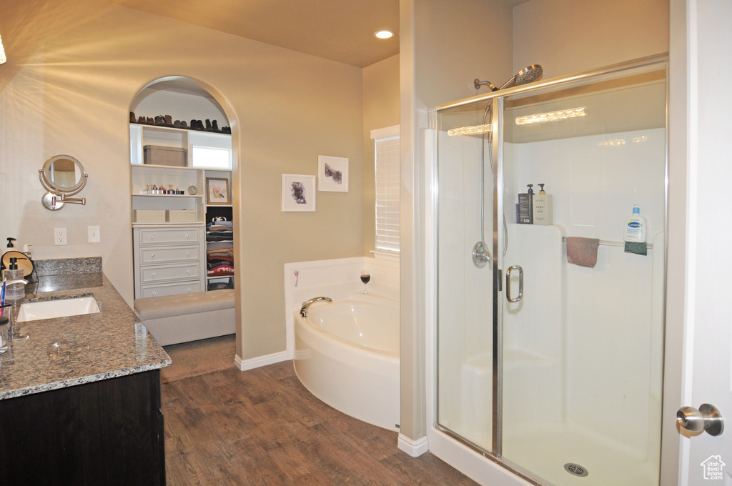 Bathroom with wood-type flooring, shower with separate bathtub, and vanity