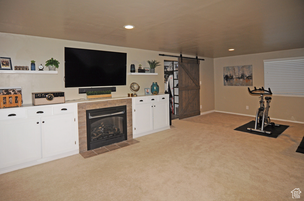 Interior space with a tile fireplace, light colored carpet, and a barn door